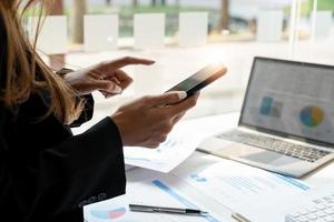 primo piano donna d'affari uso di smart phone per la contabilità finanziaria in ufficio foto