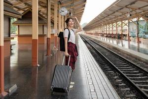 donna asiatica viaggiatore zaino in spalla piano vacanze estive dopo il coronavirus. turisti vuoti sui binari del treno. utilizzare autobus treno trasporto sostenibile rispettoso dell'ambiente foto