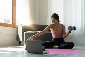 la giovane donna sta esercitando lo yoga a casa. fitness, allenamento, vita sana e concetto di dieta foto