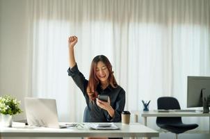 ritratto di donna asiatica felice giovane business che celebra il successo con le braccia in su. espressione positiva, successo nel concetto di business foto