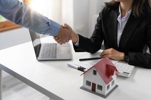 agenti immobiliari e clienti si stringono la mano per congratularsi per aver firmato un contratto per l'acquisto di una casa con terreno e assicurazione, stretta di mano e buon concetto di risposta foto