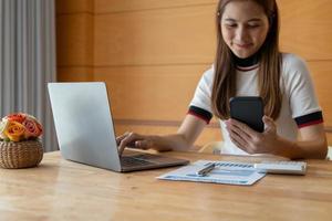 la mano asiatica della donna che utilizza lo smartphone calcola per l'analisi e la contabilità finanziaria di bilancio con il grafico delle statistiche di crescita e il grafico su scartoffie. concetto finanziario di contabilità foto