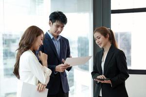 uomini d'affari asiatici che hanno una riunione di lavoro. felice team aziendale diversificato, giovani e vecchi lavoratori che parlano di brainstorming sul progetto in ufficio foto