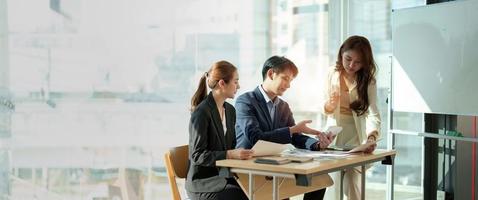 gruppo di persone asiatiche d'affari che lavorano sul grafico, parlando, pianificando, analizzano gli investimenti e il marketing su tablet in ufficio. scatto panoramico. foto