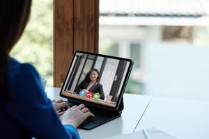 app per la comunicazione con i dipendenti. videoconferenza on line. la donna comunica tramite videochiamata con i partner commerciali, si siede nello spazio ufficio moderno e creativo. foto