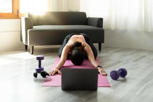 istruttore di fitness con lezione di yoga virtuale tramite videochiamata sul laptop. l'insegnante di yoga a distanza conduce una lezione per le persone foto