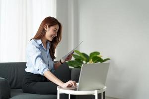 attraente donna asiatica che lavora per le finanze con computer portatile e scartoffie a casa. foto