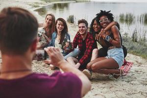 sorrisi sinceri. un gruppo di persone fa un picnic sulla spiaggia. gli amici si divertono durante il fine settimana foto