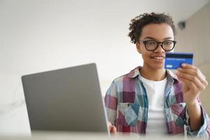 pagamento online, trasferimento di denaro. bella ragazza afro sta comprando online con carta di credito. foto