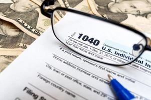 Modulo di dichiarazione dei redditi individuale 1040 attraverso occhiali e contanti
