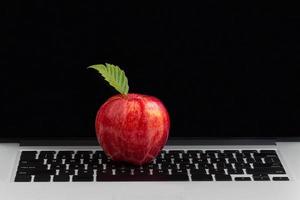 mela rossa fresca in cima alla tastiera del computer portatile foto