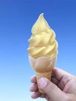 man mano che tiene un cono gelato sullo sfondo. il cielo azzurro foto