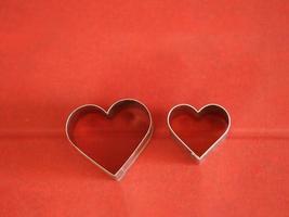 stampi per pane a forma di cuore in acciaio su sfondo rosso, amore San Valentino per la copia della scheda di testo, sfondo foto