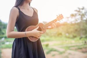 bella donna che tiene una chitarra sulla spalla, estate parco naturale fuori. foto