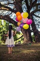 bambina con palloncini in un campo foto
