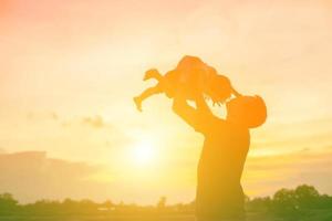 il padre ha preso il bambino impara a camminare al tramonto. foto