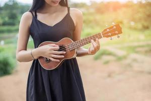 bella donna che tiene una chitarra sulla spalla, estate parco naturale fuori. foto