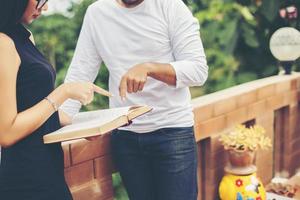 pratica di educazione dei giovani insieme digitando a mano sul laptop e leggendo un libro. foto