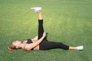 donna sportiva su un prato che fa yoga da solo. pilates e stretching foto