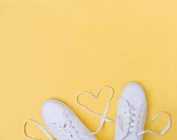 scarpe da ginnastica bianche con lacci a forma di cuore su sfondo giallo foto