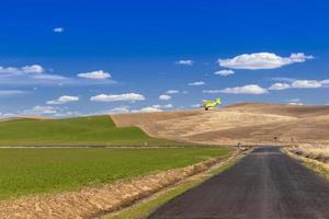 Lo spolverino per colture vola sulle dolci colline del palouse spruzzando fertilizzante, Washington, Stati Uniti foto