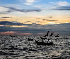 drammatico tramonto sul mare con barca da pesca foto