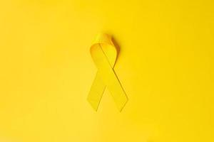 nastro giallo su sfondo giallo per sostenere le persone che vivono e le malattie. giornata di prevenzione del suicidio di settembre, mese di sensibilizzazione sul cancro infantile e concetto di giornata mondiale del cancro foto