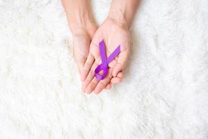 cancro al pancreas, alzheimer mondiale, epilessia, lupus e mese di sensibilizzazione sulla violenza domestica, donna che tiene un nastro viola per sostenere le persone che vivono. concetto di salute e giornata mondiale del cancro foto