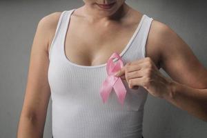 mani di donna che tengono nastri rosa per la consapevolezza del cancro al seno, cancro al seno. concetto di assistenza sanitaria e medicina. foto