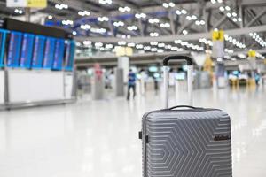 borsa per bagagli nel terminal dell'aeroporto internazionale, valigia trolley con pannello informativo sullo sfondo dell'aeroporto. concetti di trasporto, assicurazione, viaggi e vacanze foto