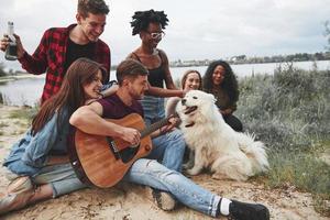 diversità di persone. fare un picnic sulla spiaggia. gli amici si divertono durante il fine settimana foto