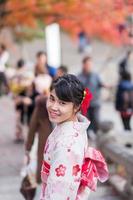 giovane turista che indossa un kimono godendo con foglie colorate nel tempio di kiyomizu dera, kyoto, giappone. ragazza asiatica con acconciatura in abiti tradizionali giapponesi nella stagione del fogliame autunnale foto