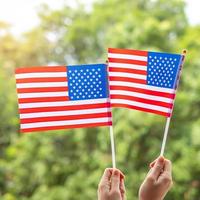 mano che tiene la bandiera degli stati uniti d'america su sfondo verde. festa degli Stati Uniti dei veterani, memoriale, indipendenza e concetto di festa del lavoro foto