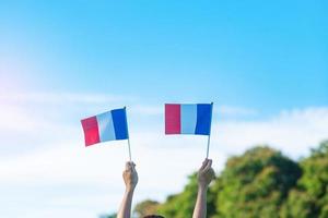 mano che tiene la bandiera della francia su sfondo blu cielo. festa della festa nazionale francese, giorno della bastiglia e felici concetti di celebrazione foto