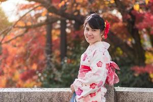 giovane turista che indossa un kimono godendo con foglie colorate nel tempio di kiyomizu dera, kyoto, giappone. ragazza asiatica con acconciatura in abiti tradizionali giapponesi nella stagione del fogliame autunnale foto