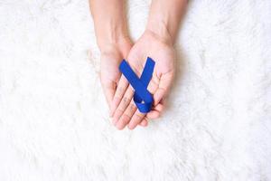 marzo mese di sensibilizzazione sul cancro colorettale, uomo che tiene un nastro blu scuro per sostenere le persone che vivono e le malattie. concetto di assistenza sanitaria, speranza e giornata mondiale del cancro foto