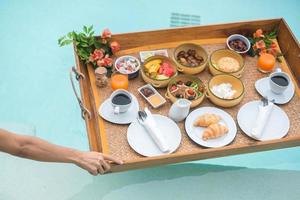 avendo un vassoio per la colazione galleggiante in un hotel di lusso con piscina, la ragazza si diverte in un resort tropicale. viaggi estivi rilassanti, esotici, vacanze, vacanze e tropicali foto