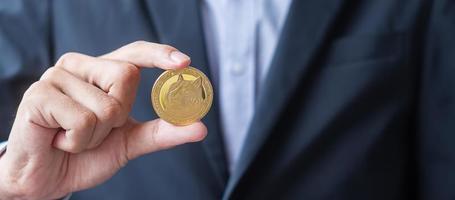 mano d'uomo d'affari che tiene criptovaluta dogecoin d'oro, la cripto è denaro digitale all'interno della rete blockchain, viene scambiata utilizzando la tecnologia e lo scambio online. concetto finanziario decentralizzato foto