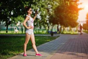 abbigliamento sportivo da ragazza su pantaloncini bianchi e camicia che fa selfie al parco. foto