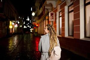 ragazza con i dreadlocks che cammina di notte per la strada della città. foto