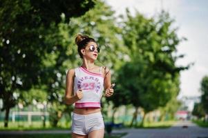 abbigliamento sportivo da ragazza su pantaloncini bianchi e camicia che corre al parco. foto