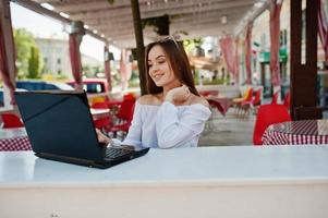 ritratto di una forte imprenditrice di successo indipendente che indossa abiti casual intelligenti e occhiali che lavorano su un laptop in un caffè.