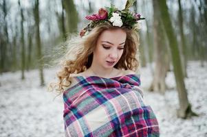 ragazza bionda riccia carina con corona in plaid a scacchi nella foresta innevata nella giornata invernale. foto