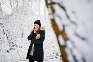 bella ragazza bruna in abiti caldi invernali. modello su giacca invernale e cappello nero. foto