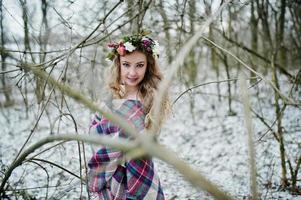 ragazza bionda riccia carina con corona in plaid a scacchi nella foresta innevata nella giornata invernale. foto