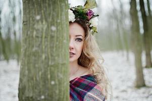 ragazza bionda riccia carina con corona in plaid a scacchi nella foresta innevata nella giornata invernale. foto