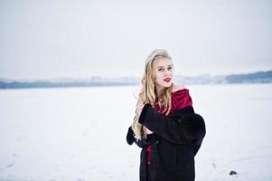 eleganza bionda ragazza in pelliccia e abito da sera rosso poste in inverno nevoso giorno. foto