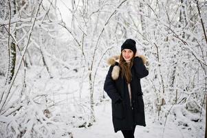 bella ragazza bruna in abiti caldi invernali. modello su giacca invernale e cappello nero. foto