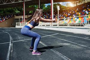 ritratto di una splendida ragazza che fa squat nello stadio. foto