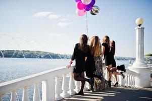 il retro di cinque ragazze indossa il nero con palloncini all'addio al nubilato contro il lago. foto